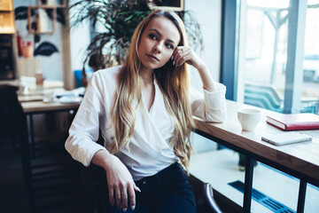 Fototapeta premium Pensive young woman having rest in cafe with cup of hot drink