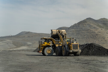 A loader loads ore into a dump truck at the gold mine site.
