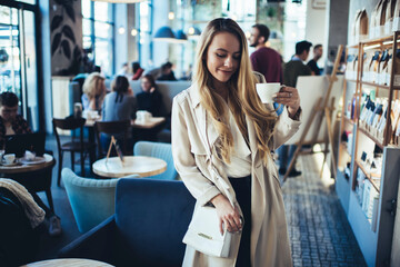 Cheerful woman having hot drink in cafeteria
