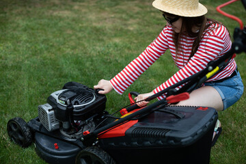 A girl unscrews the fuel filler tap on a garden mower.