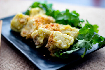 Chinese Steamed Dumpling served in a black plate on a wooden table. along with cilantro.