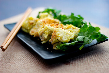 Chinese Steamed Dumpling served in a black plate on a wooden table. along with cilantro.