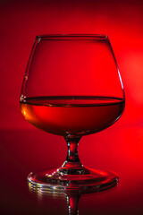 glass with cognac on a red gradient background