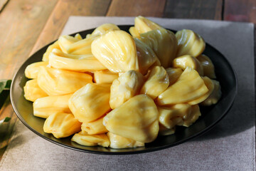Thai fruit, fresh jackfruit placed in a black plate on a wooden table.