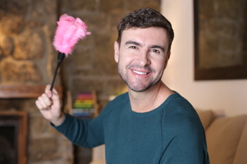 Male housekeeper holding pink feather duster
