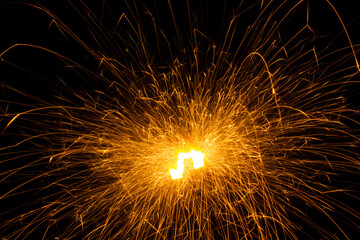 Close-up short exposure photo of a single burning sparkler, producing lots of pink bright hot sparks