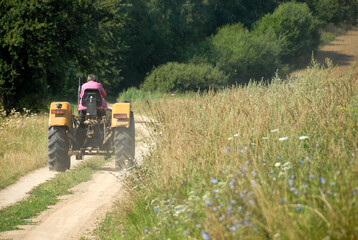 Poland - June 2018: Unpaved road between fields, Agricultural machine on the road