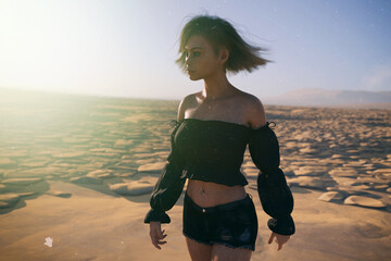 Blond woman with wind in her hair in a black shirt in a sunny desolate dry landscape. 3D render.