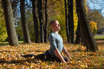 Sporty man practicing yoga in autumn park