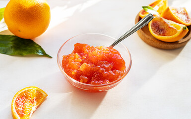 Red oranges' jam in glass bowl with fruits