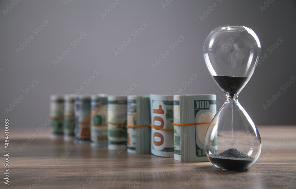 Wall mural Hourglass and money on the desk. Time is money