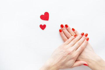 Nail care and manicure. Beautiful female hands with a red nail and a red heart. Place for an inscription. Valentine's Day.