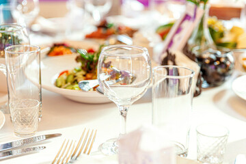 Fancy table set for dinner with napkin glasses in restaurant, luxury interior background. Wedding elegant banquet decoration and items for food arranged by catering service on white tablecloth table