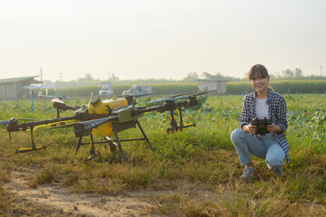 Young smart farmer controlling drone spraying fertilizer and pesticide over farmland,High technology innovations and smart farming