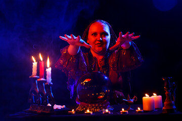 fortune teller in the salon read the future in a crystal ball in smoke on a black background.