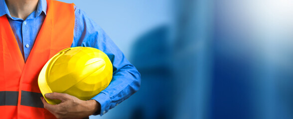 Construction worker. hand of worker with yellow hard-hat on constraction background. Helmet in construction