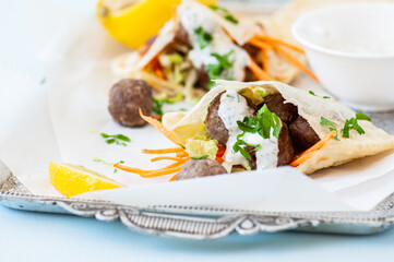 Homemade lamb meatballs in pita flatbread with spicy yoghurt sauce. Close up.