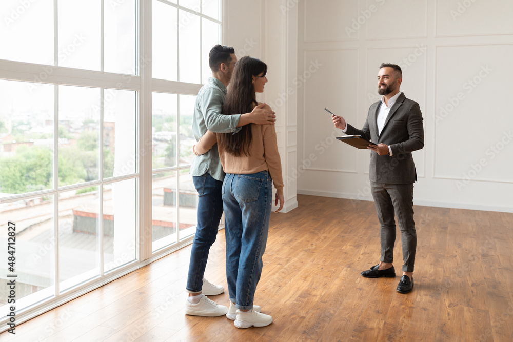 Poster estate agent in suit showing buyers new apartment