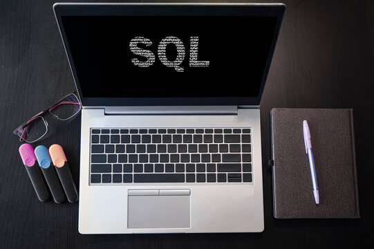 Top view of laptop with text SQL. SQL inscription on laptop screen and keyboard. Learn SQL language, computer courses, training.
