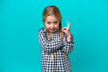 Little caucasian girl isolated on blue background showing ok sign with fingers