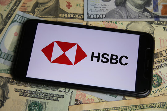 Viersen, Germany - January 9. 2022: Closeup of mobile phone with logo of hsbc , us dollar paper banknotes background