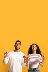 Check This. Joyful Young Arab Couple Pointing Up At Copy Space