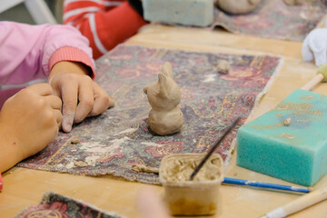 A child molds a product from clay in a modeling lesson.