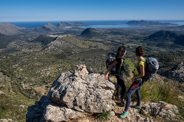 Fototapeta premium hikers ascending Cucuia de Fartaritx with Alcudia bay in the background, Pollença, Mallorca, Balearic Islands, Spain