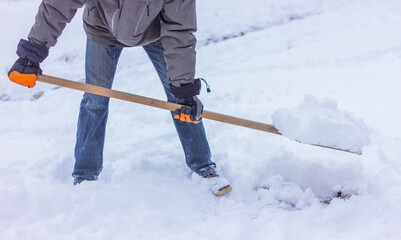 Naklejka premium a man removes snow on the outdoor with a special flat shovel. winter seasonal yard cleaning and activities.