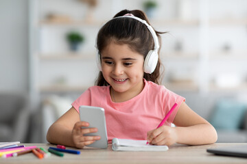 Remote Education. Girl In Headphones Using Smartphone At Home For Distance Learning
