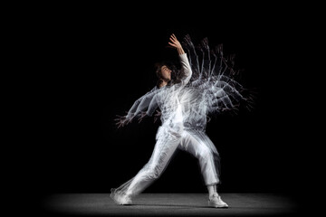 Young man, hip-hop dancer in action, motion isolated on dark background with sroboscope effect....