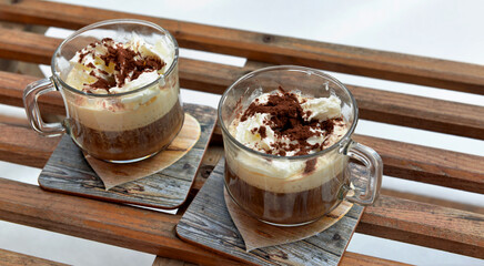 two cups of cappuccino placed on an old wooden sled in the  snow