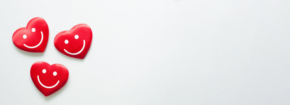 Three red hearts with smile emoticons on white background. Web banner.