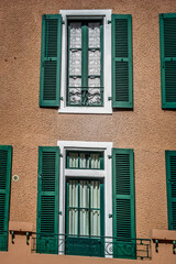 European street. Wooden shutters. Facade of a residential building. Travel in Europe. Open and closed shutters. French windows.