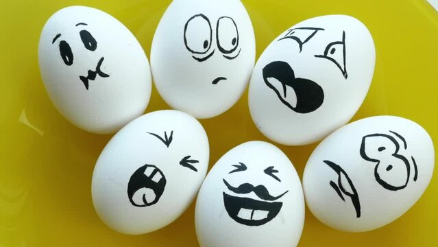 Boiled white eggs with funny emotional faces on a yellow plate. Fear, anger, contempt, laughter, joy, surprise, annoyance. Easter.