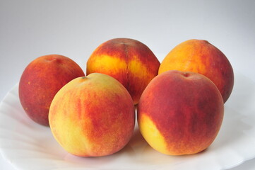 Fototapeta na wymiar Bright, juicy peaches on a white dish