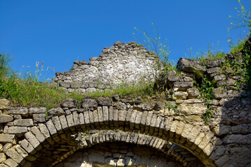 Ruins of an ancient Christian temple against blue sky. Collapsed ceiling. Masonry, room with arched vaults. Grass grows on walls. Rashkov, Moldova. Close-up.