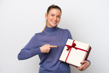 Young caucasian woman holding a gift isolated on white background and pointing it