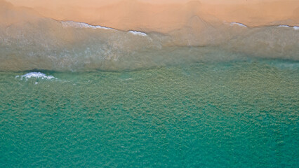 Aerial view of turquoise ocean wave reaching the coastline. Beautiful tropical beach from top view....
