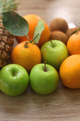 Pineapple, apples, oranges, lemons and kiwis on a wooden table. Selective focus. 