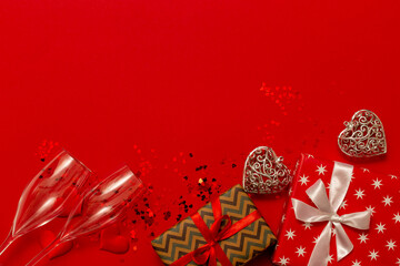 champagne glasses, red gift boxes with ribbon bows on a red background and beautiful silver hearts....