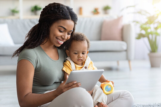 Black Woman And Her Adorable Infant Son Using Digital Tablet At Home