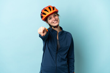 Young cyclist woman isolated on blue background pointing front with happy expression - obrazy, fototapety, plakaty