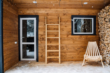 Obraz na płótnie Canvas Garden chaise longue for outdoor seating made of wood. Logs. Chopped birch firewood in a log. Wooden staircase against the wall. Modular house with plastic windows