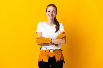 Young electrician woman isolated on yellow background keeping the arms crossed in frontal position