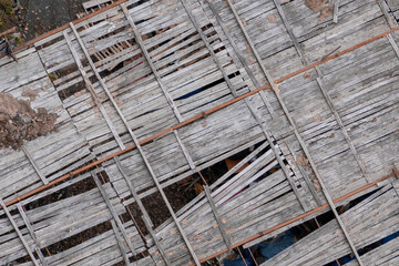 Top view of abandoned building with an unfinished wooden roof and junk around. Close up.