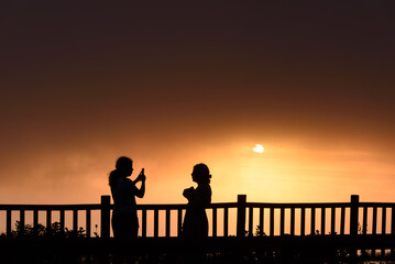 Fototapeta na wymiar Silhoutte of Two Young Adult Women Standing on Sunset Sun