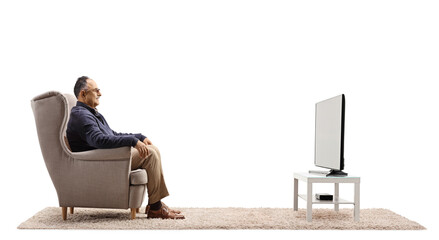 Profile shot of a casual mature man sitting in an armchair and watching tv