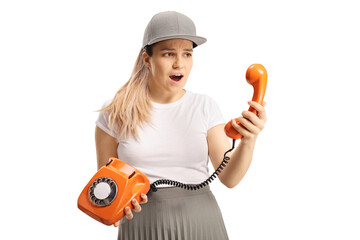 Surprised young female using an old vintage rotary dial phone