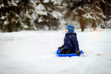 Fototapeta na wymiar little boy sitting on snow saucer in winter park
